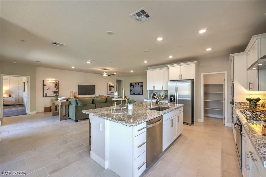 1032 Gentle Swan Street, Henderson, NV 89011 Granite countertops and an expansive island anchor this modern open-concept kitchen space.