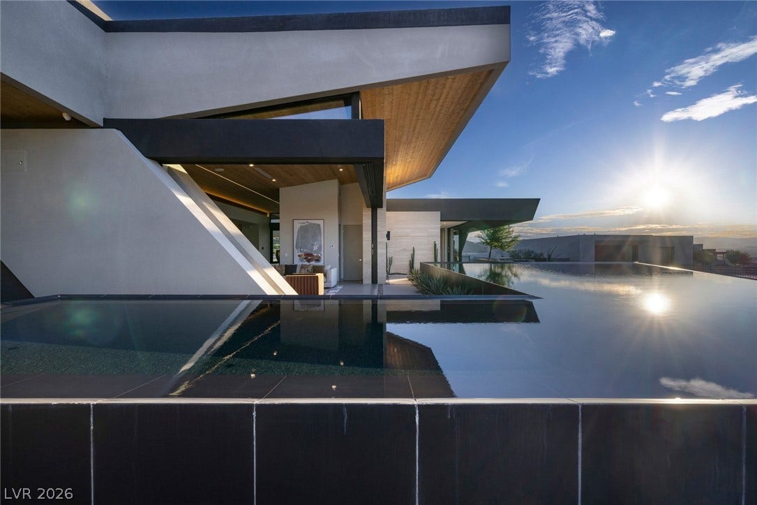 705 Dragon Peak Drive, Henderson, NV 89012 Dramatic modern architecture meets a sleek infinity pool under a vibrant afternoon sky.