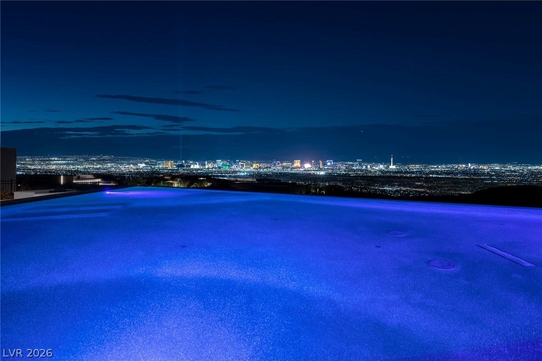 705 Dragon Peak Drive, Henderson, NV 89012 An illuminated infinity-edge pool frames a panoramic view of the sparkling city skyline at night.