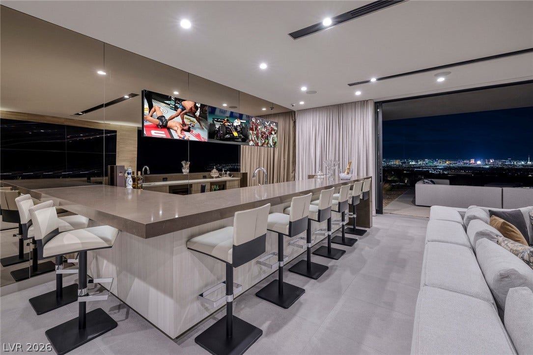 705 Dragon Peak Drive, Henderson, NV 89012 An expansive wet bar with stone counters transitions seamlessly to outdoor spaces through sliding glass doors.
