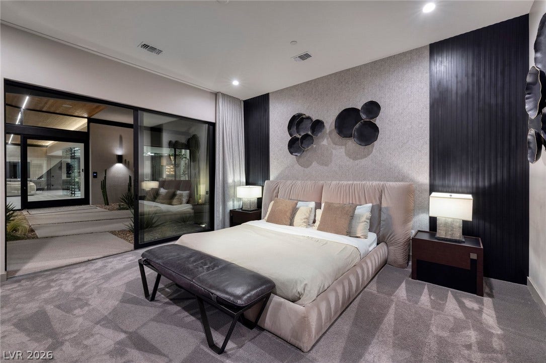 705 Dragon Peak Drive, Henderson, NV 89012 A spacious bedroom with plush carpeting features sliding glass doors that open to a courtyard.
