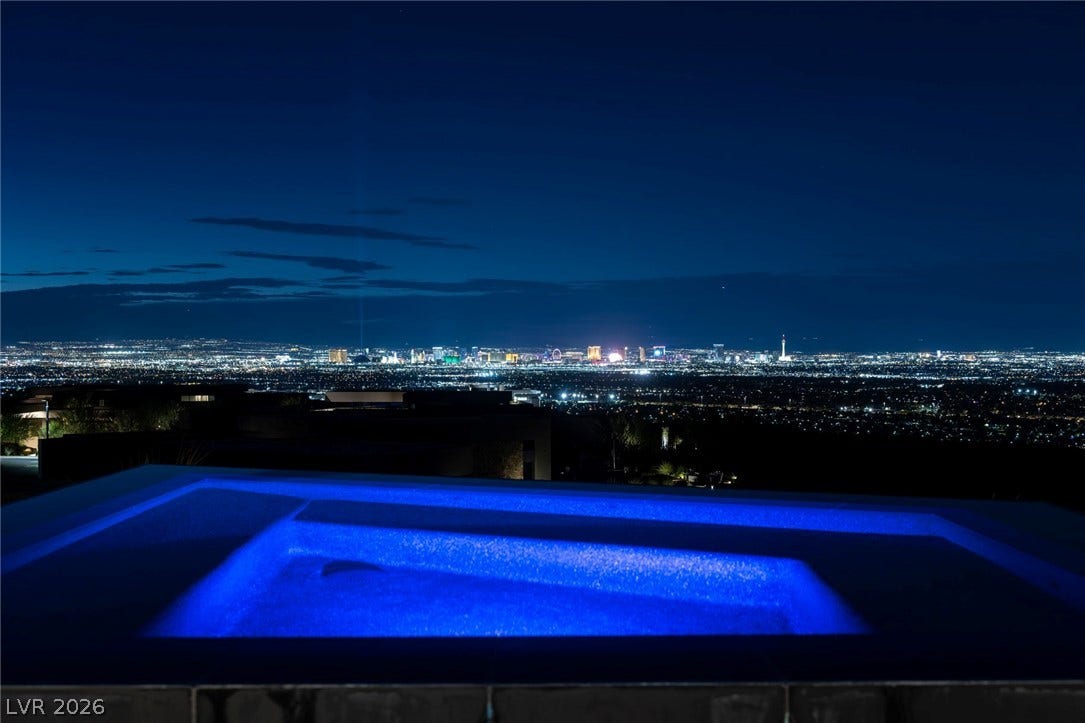 705 Dragon Peak Drive, Henderson, NV 89012 Glittering city lights stretch across the horizon beyond an illuminated pool at dusk.