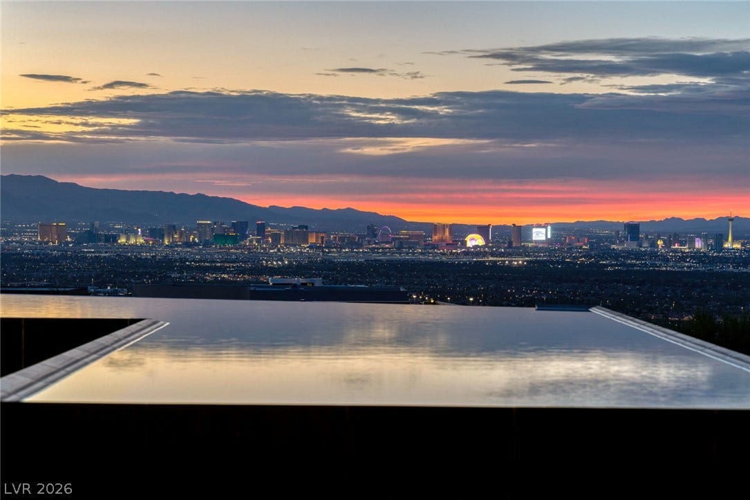 705 Dragon Peak Drive, Henderson, NV 89012 An infinity pool reflects dramatic sunset skies above a sparkling city skyline.