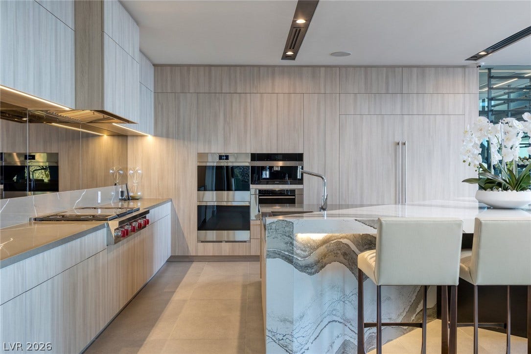 705 Dragon Peak Drive, Henderson, NV 89012 Streamlined wooden cabinetry and a dramatic stone island define this contemporary culinary space.