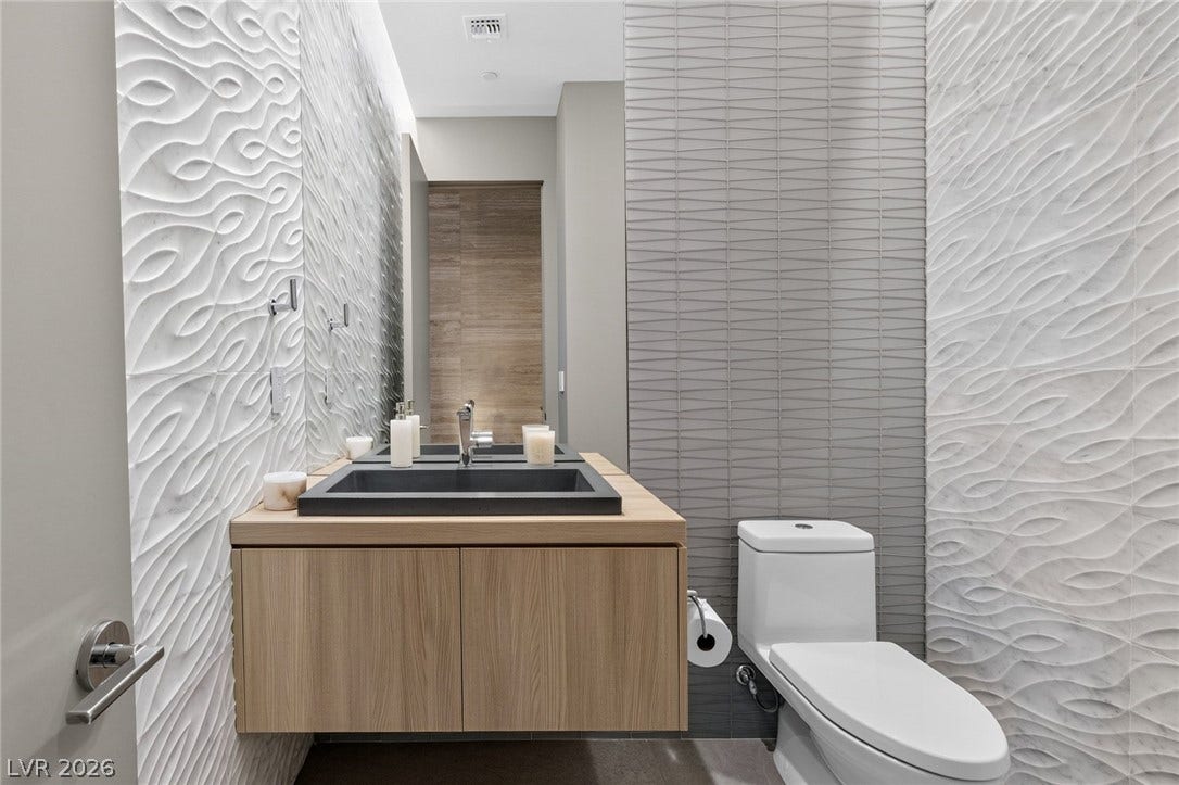705 Dragon Peak Drive, Henderson, NV 89012 Textured wall tiles and a floating double vanity elevate this modern bathroom design.