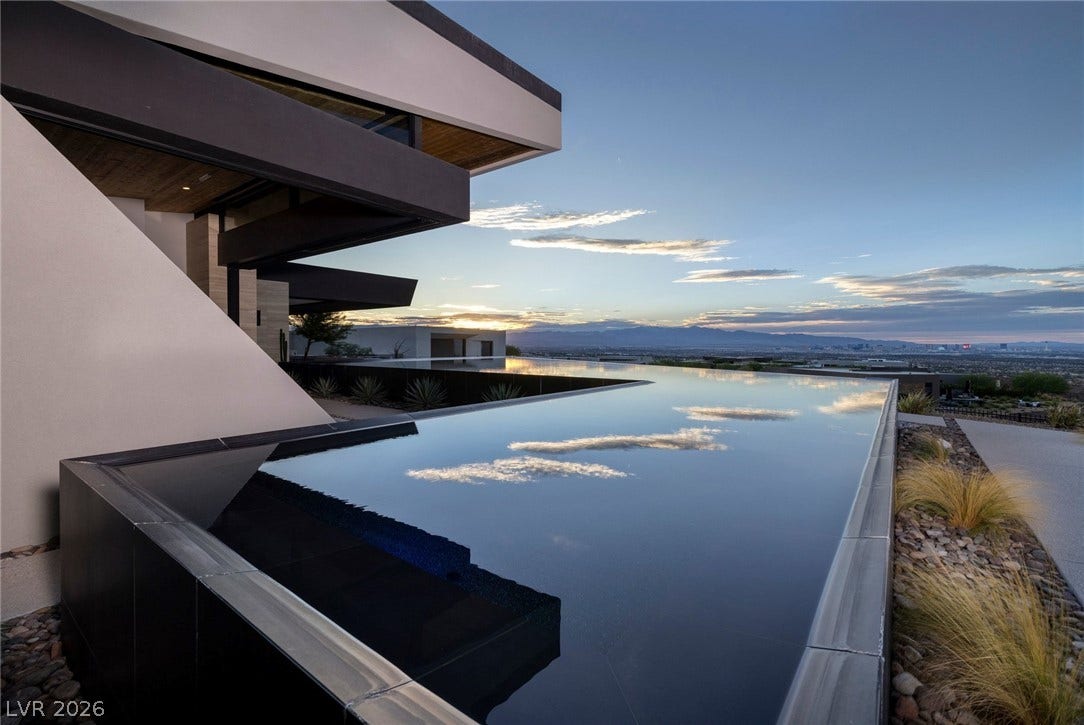 705 Dragon Peak Drive, Henderson, NV 89012 Dramatic modern architecture frames a massive infinity pool overlooking distant city lights and mountains.