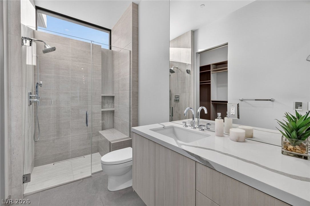 705 Dragon Peak Drive, Henderson, NV 89012 A glass-enclosed walk-in shower highlights this modern bathroom with a stone-countertop vanity.