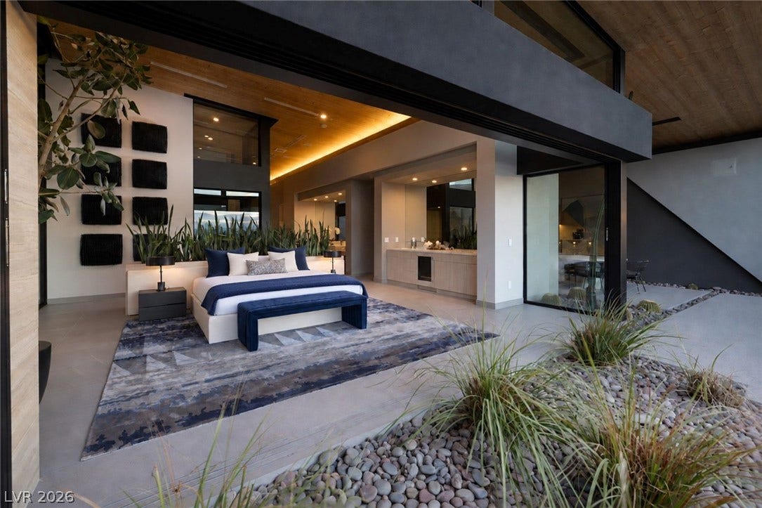 705 Dragon Peak Drive, Henderson, NV 89012 Seamless indoor-outdoor transitions define this modern bedroom featuring expansive glass doors and concrete flooring.