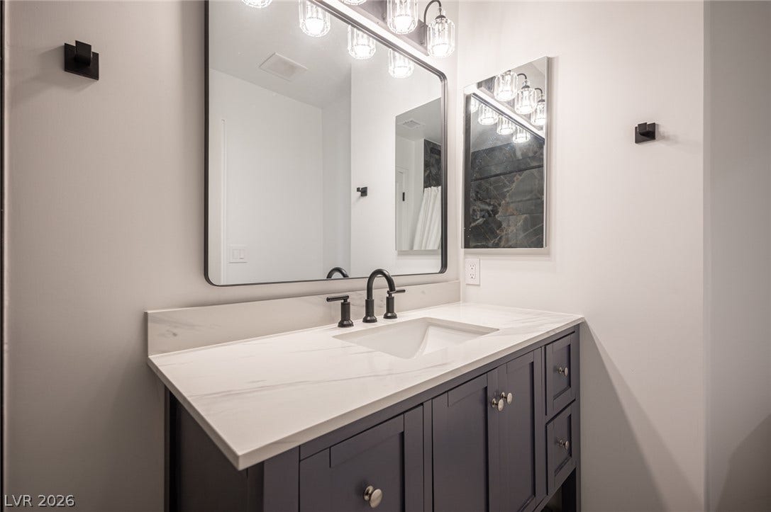 3139 Regal Oak Drive, Henderson, NV 89014 A modern vanity with stone counters and sleek black fixtures highlights this bathroom design.