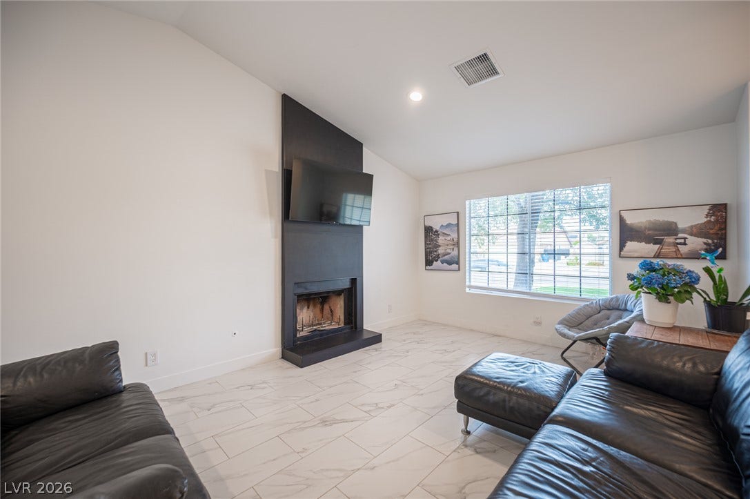 3139 Regal Oak Drive, Henderson, NV 89014 A modern fireplace anchors the living space, highlighted by vaulted ceilings and polished tile flooring.