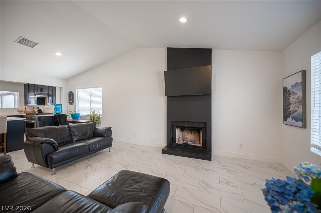 3139 Regal Oak Drive, Henderson, NV 89014 Gleaming tile floors and vaulted ceilings frame a modern fireplace in this open living area.