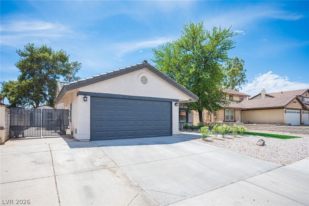 3139 Regal Oak Drive, Henderson, NV 89014 An expansive concrete driveway leads to a front-loading two-car garage with clean stucco exterior walls.
