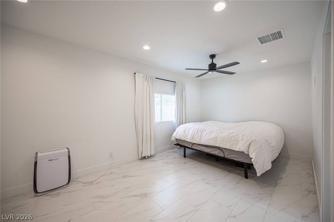 3139 Regal Oak Drive, Henderson, NV 89014 Gleaming tile floors and crisp white walls define this minimalist, modern bedroom space.