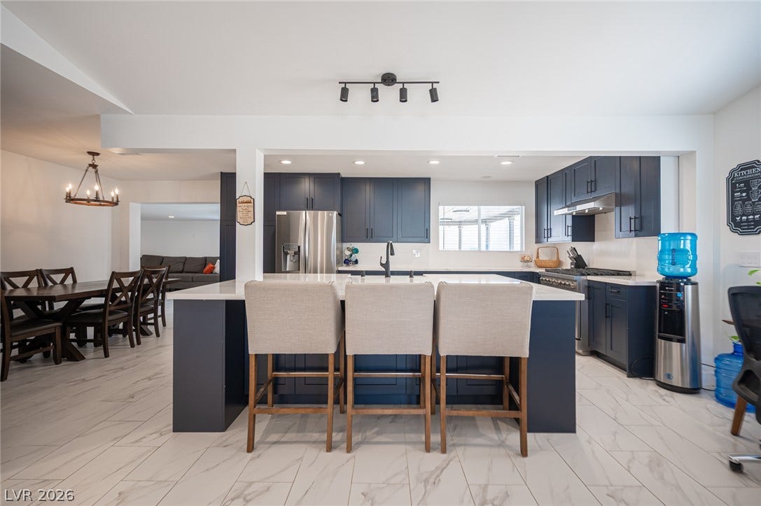3139 Regal Oak Drive, Henderson, NV 89014 Deep blue cabinetry and stone counters anchor this bright, open-plan kitchen.