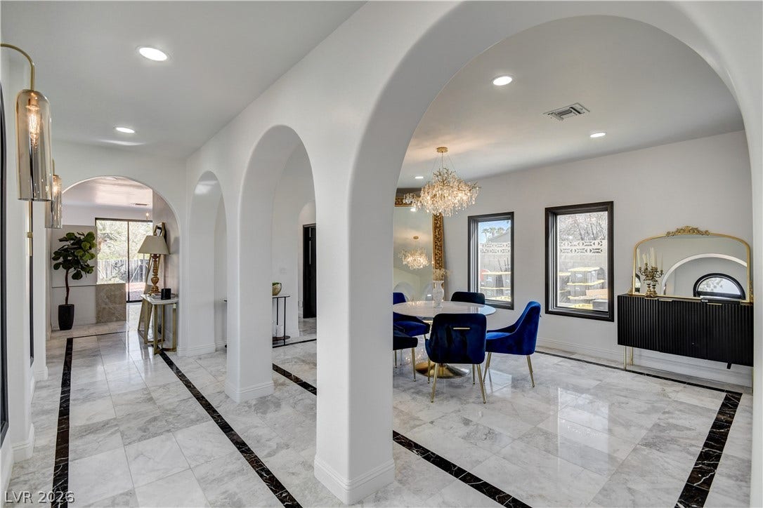 Elegant arched doorways frame a polished marble-tiled dining room illuminated by recessed lighting.
