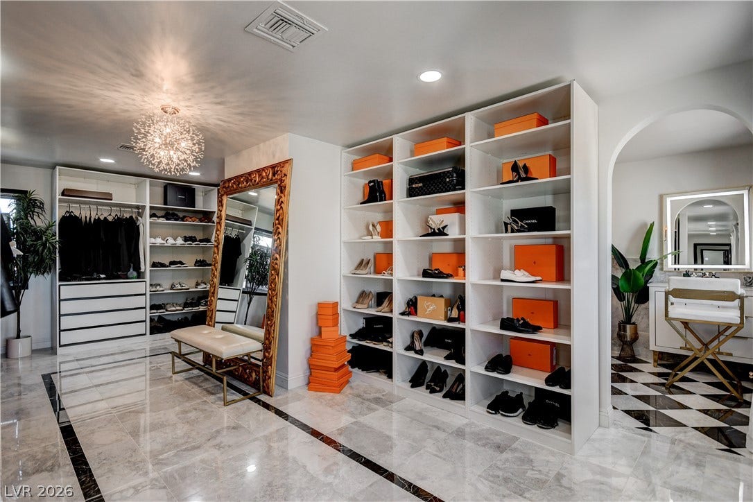 Gleaming polished stone floors and custom floor-to-ceiling built-ins elevate this grand walk-in closet space.