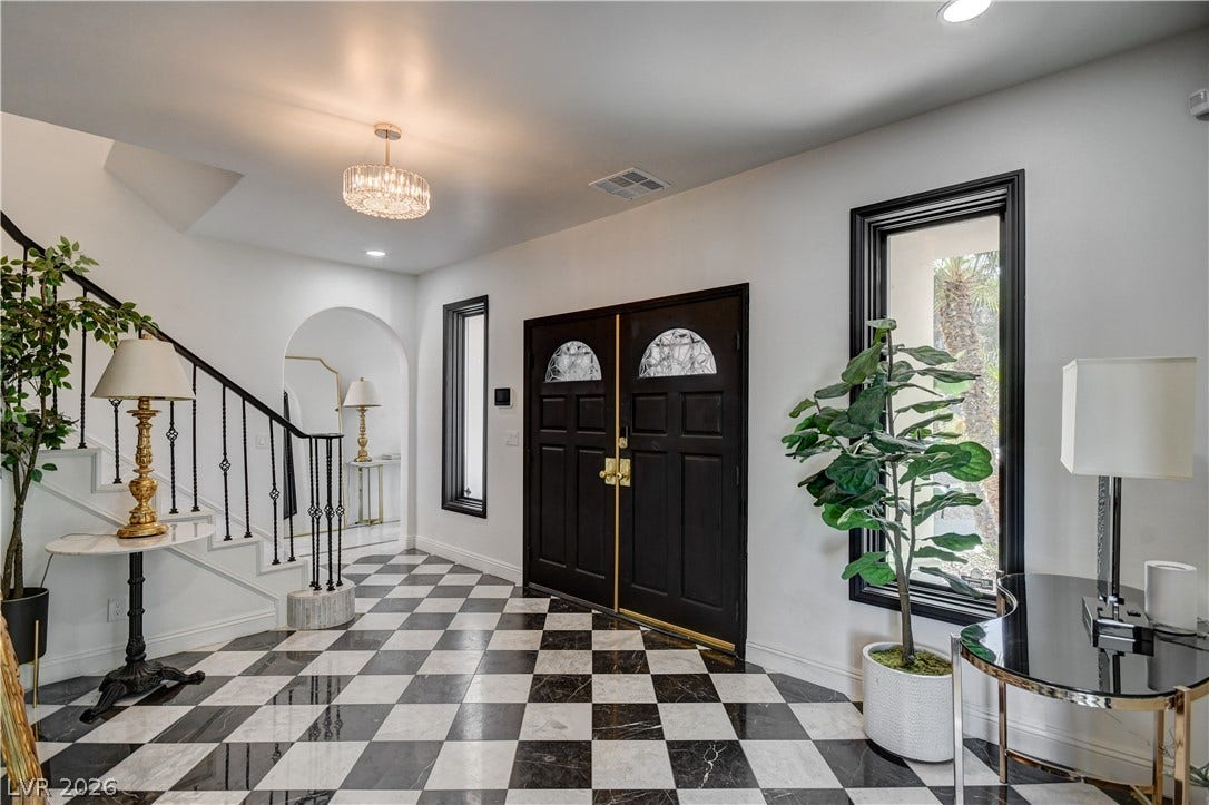 Striking checkered tile floors and a classic staircase set an elegant tone in the entryway.