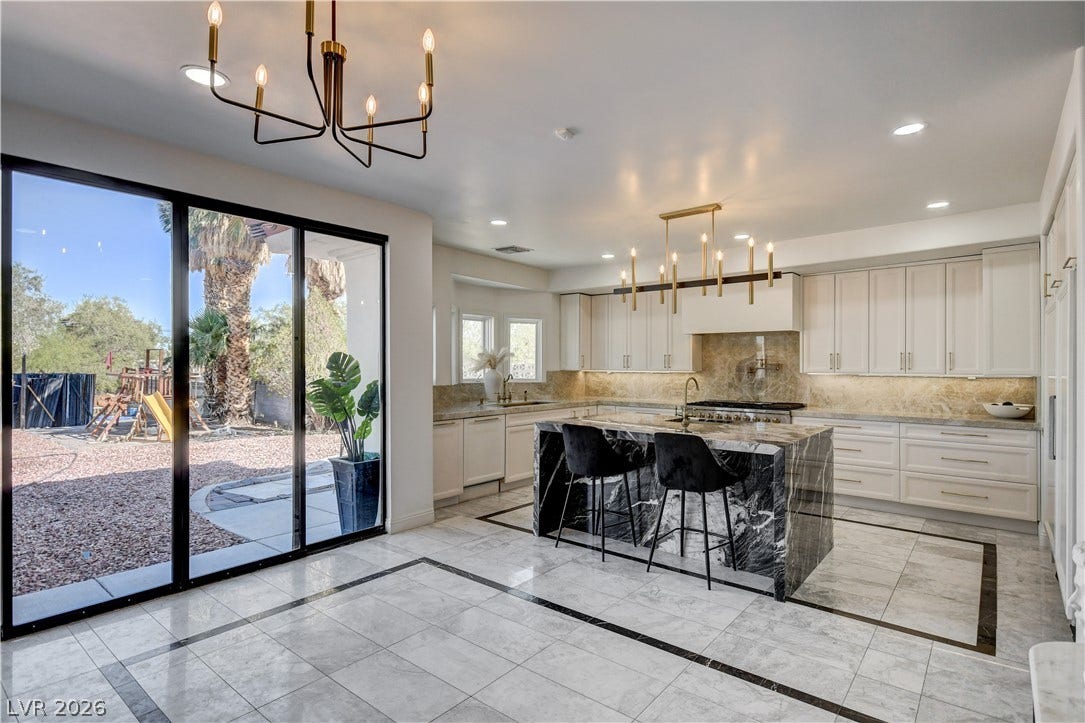 Gleaming stone tile floors and a grand marble island define this open kitchen design.