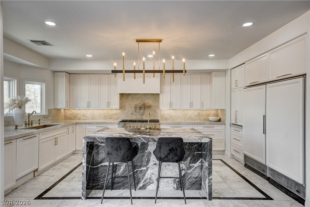 Striking stone countertops anchor this modern culinary space with clean-lined cabinetry and tiled flooring.
