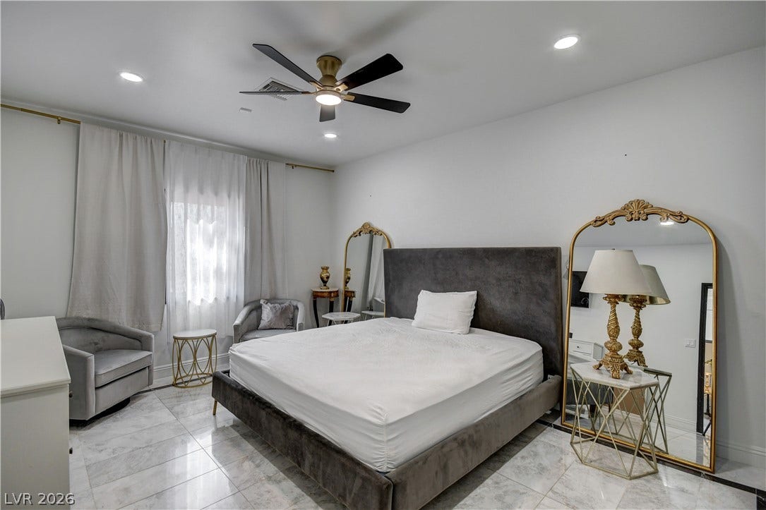 Polished tile flooring and recessed lighting define this tranquil bedroom space.