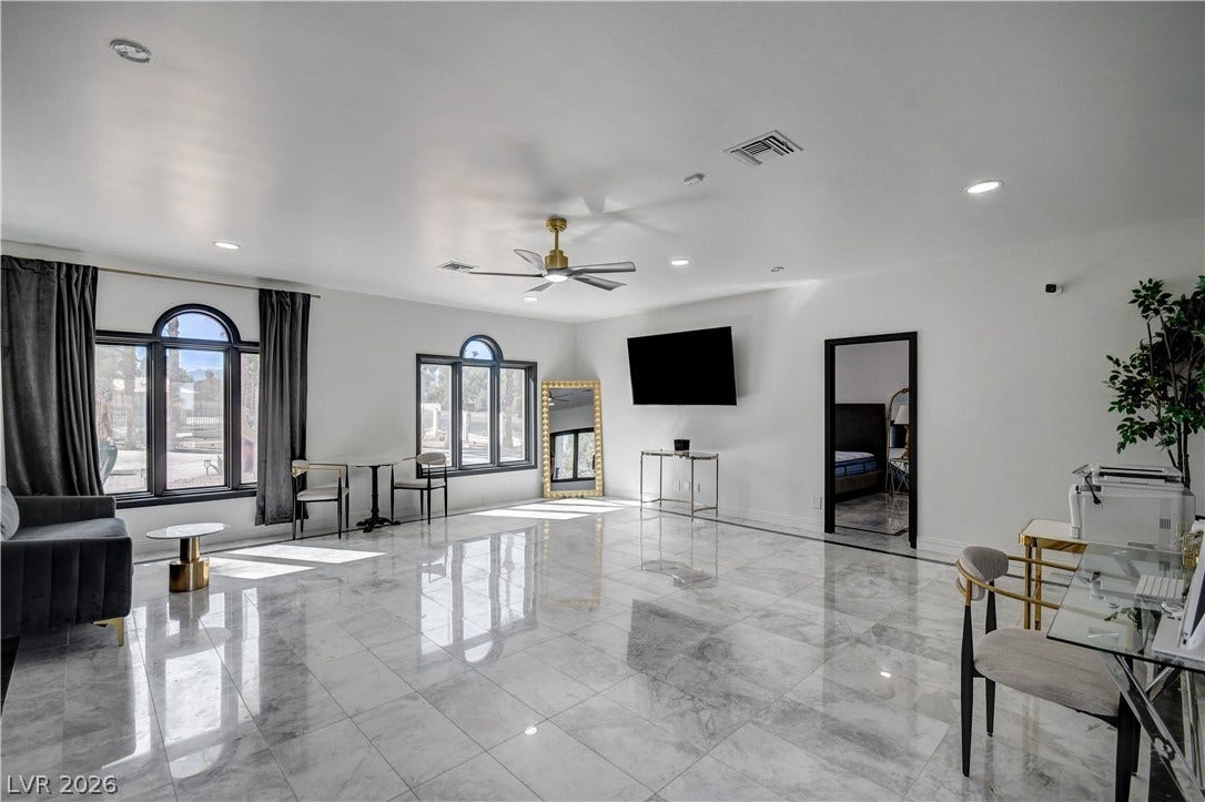 Gleaming polished tile floors reflect light beneath high ceilings in this spacious living area.