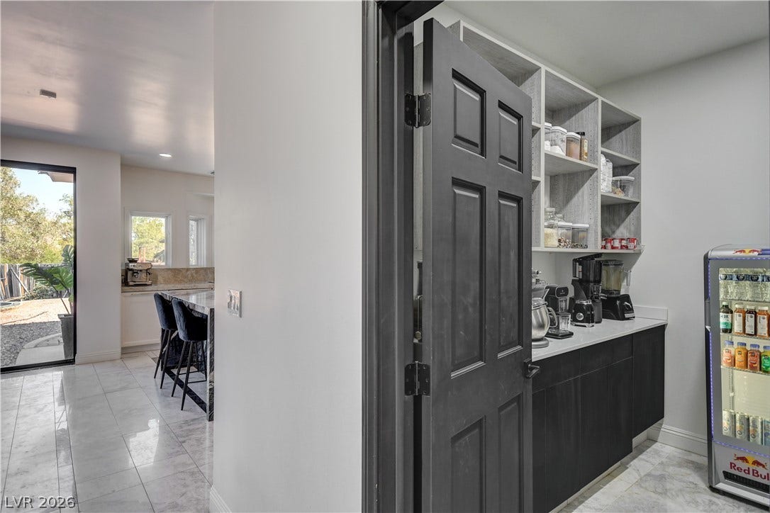 A customized walk-in pantry provides extensive built-in shelving, sleek countertops, and polished tile flooring.