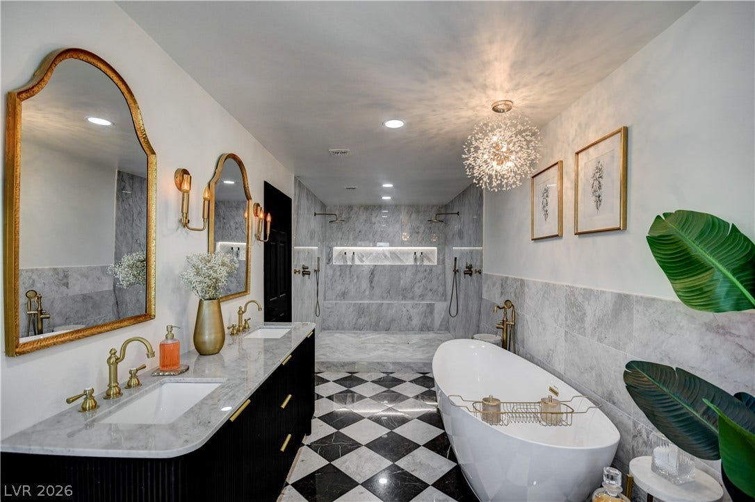 Elegant marble walls pair with checkerboard tile flooring in this expansive primary bathroom suite.