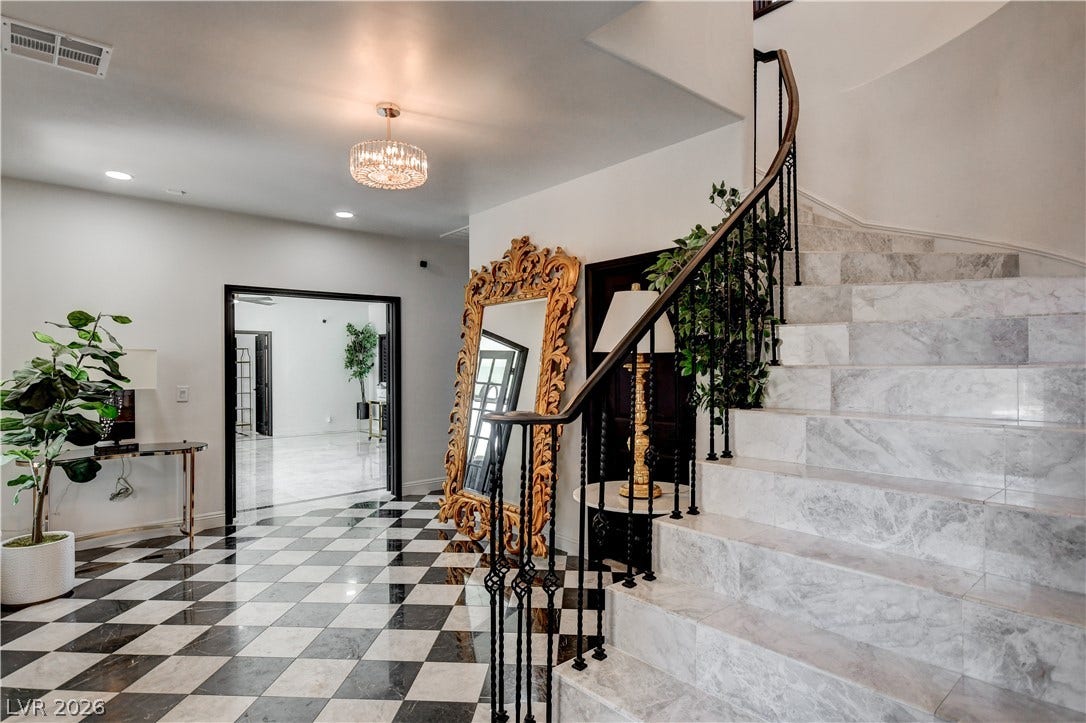 Checkerboard flooring and a grand marble staircase create an elegant, welcoming entrance foyer.