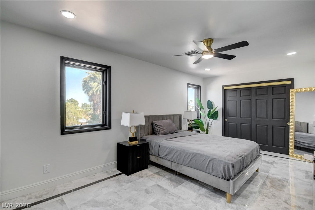 Polished stone flooring and dark wood trim define this modern bedroom.