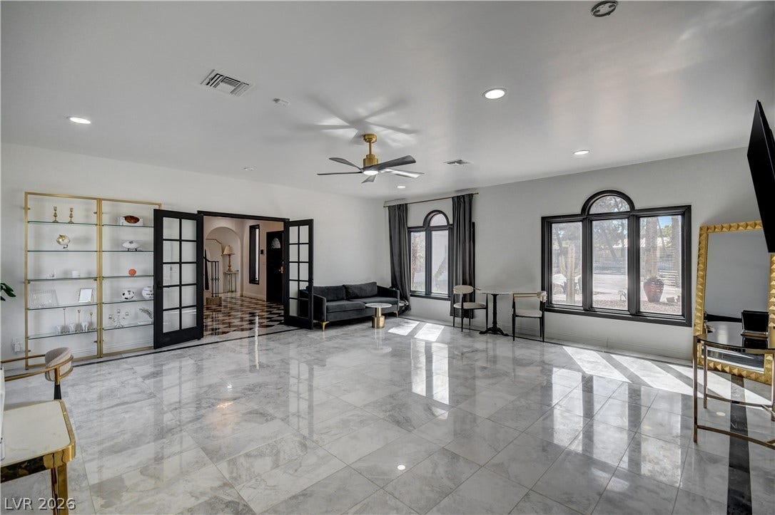 Gleaming polished tile floors reflect light beneath custom arched windows and elegant glass-paned French doors.