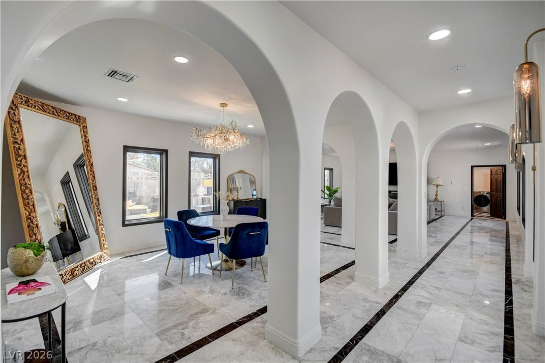 Elegant arched entryways frame a marble-tiled gallery floor and a bright dining area.