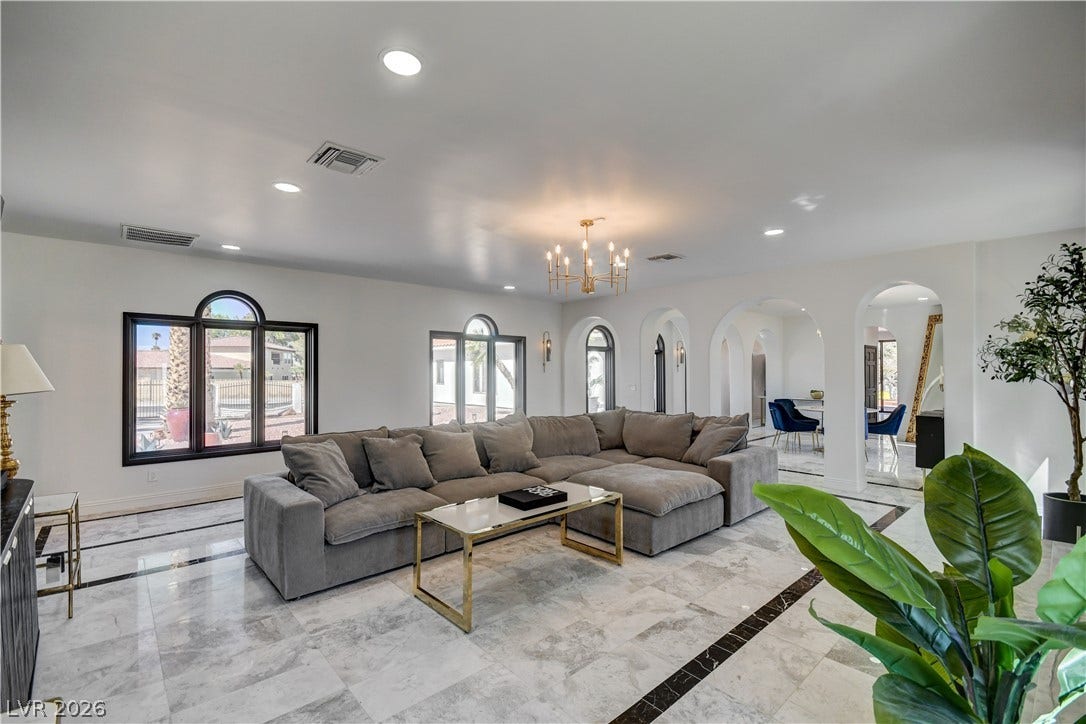 Polished tile flooring and arched doorways define this grand open living space.