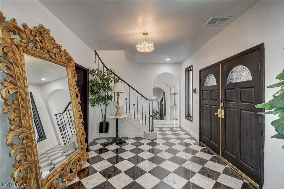 Checkerboard tile flooring and arched doorways define this grand welcoming entryway.