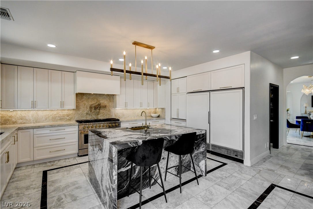 Dramatic stone surfaces elevate this culinary space anchored by a central island.