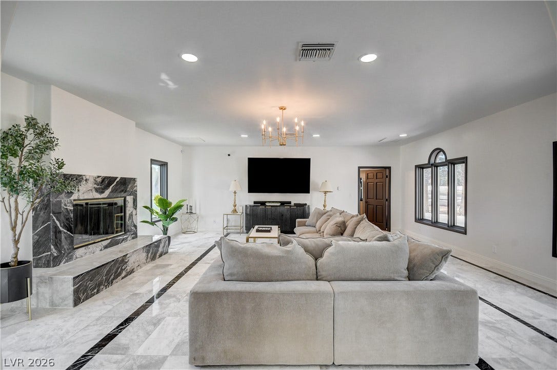 Polished tile flooring and a grand stone fireplace define this open living space.