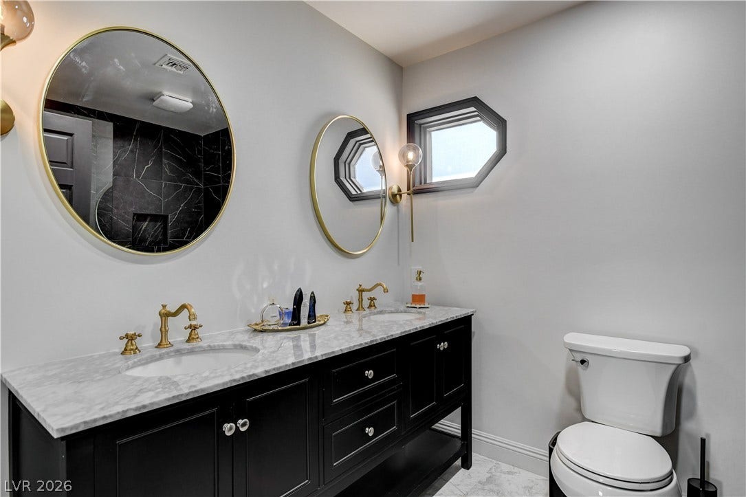 Elegance defines this space featuring a dual vanity with marble countertops and fine brass hardware.