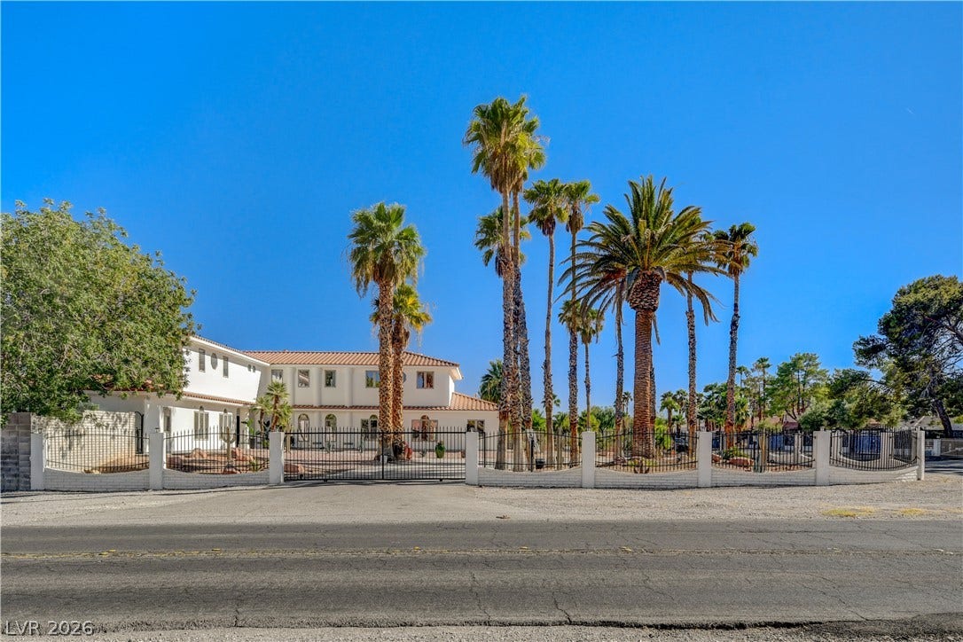 Soaring palm trees frame the gated perimeter of this elegant tile-roofed estate.