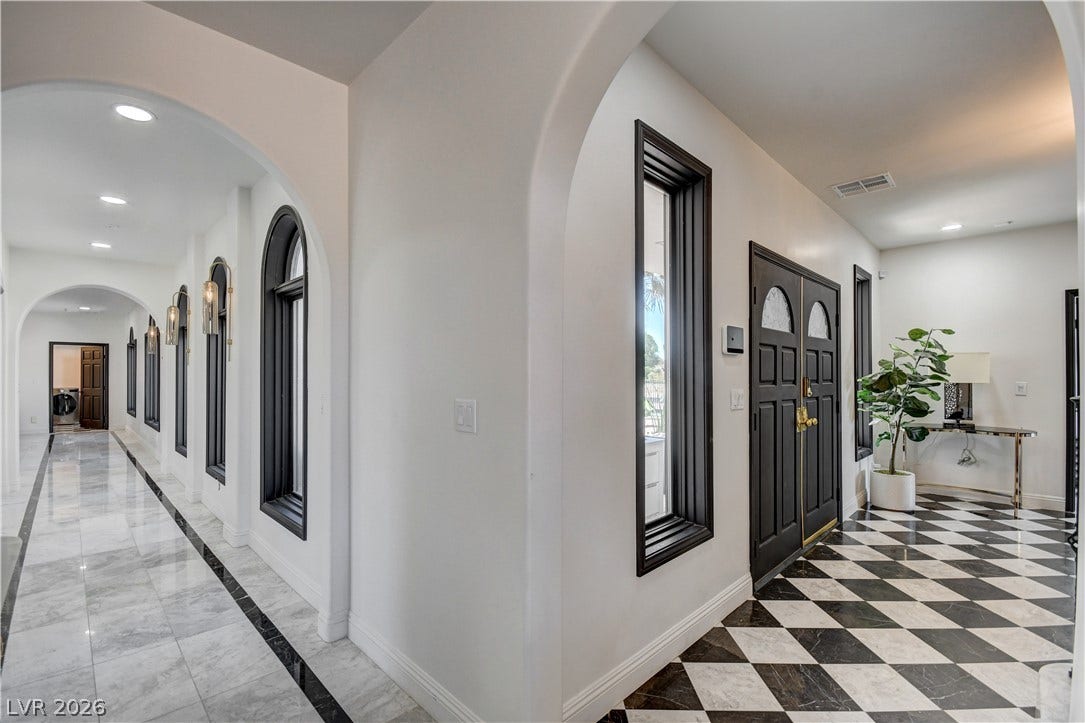 Graceful archways and polished flooring define this welcoming entry and elegant long hallway.