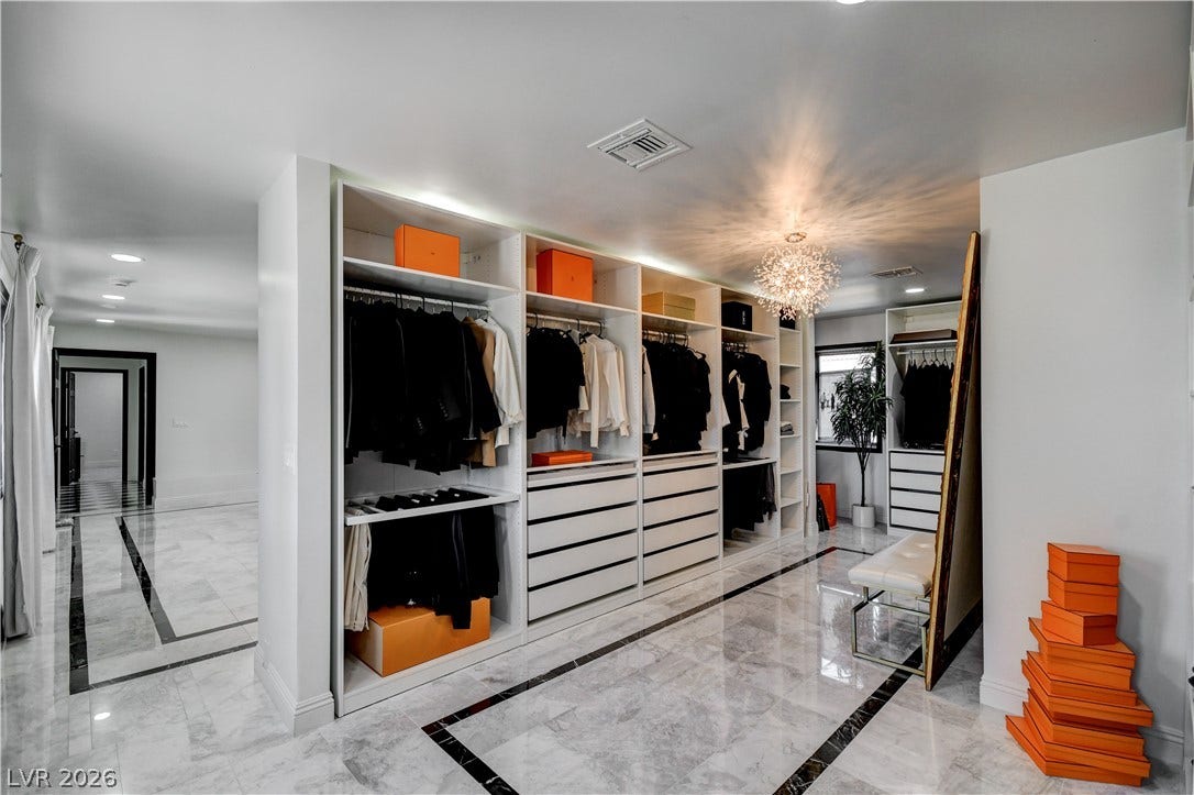 Gleaming marble flooring complements the extensive built-in storage within this spacious wardrobe area.