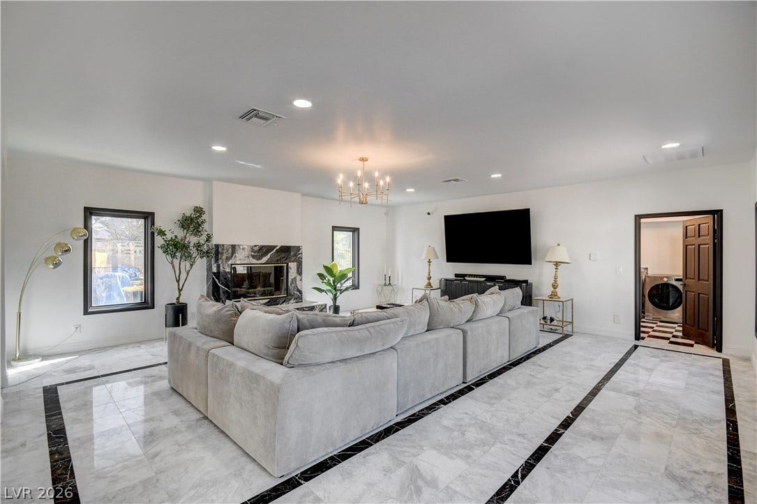 Polished stone flooring and a custom fireplace define this airy, open-concept living space.