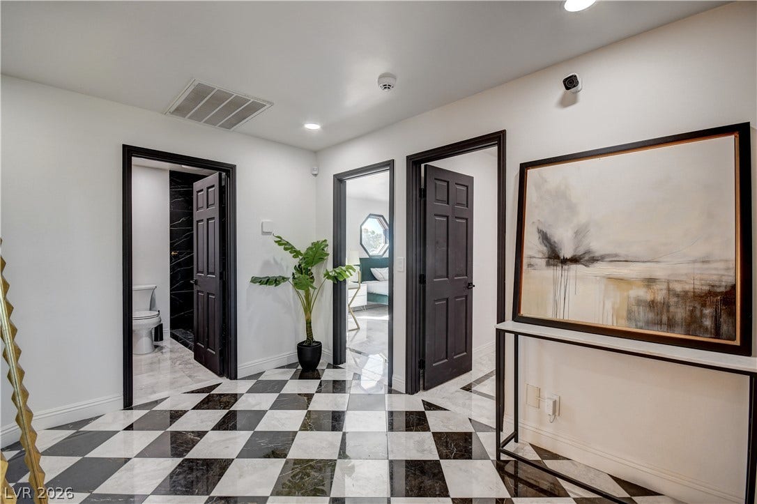 Polished checkered tile floors and dark door frames elevate this central hallway design.