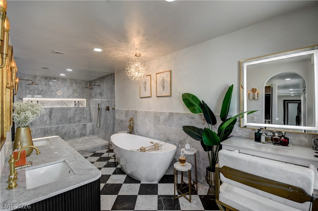 Elegant marble surfaces meet bold checkered tiling in this luxurious primary bathroom sanctuary.