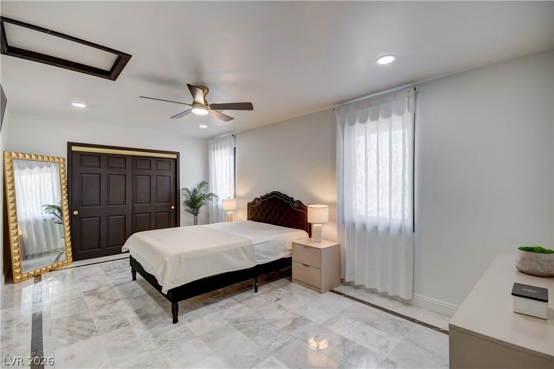 Polished tile flooring and recessed lighting define this spacious bedroom layout.