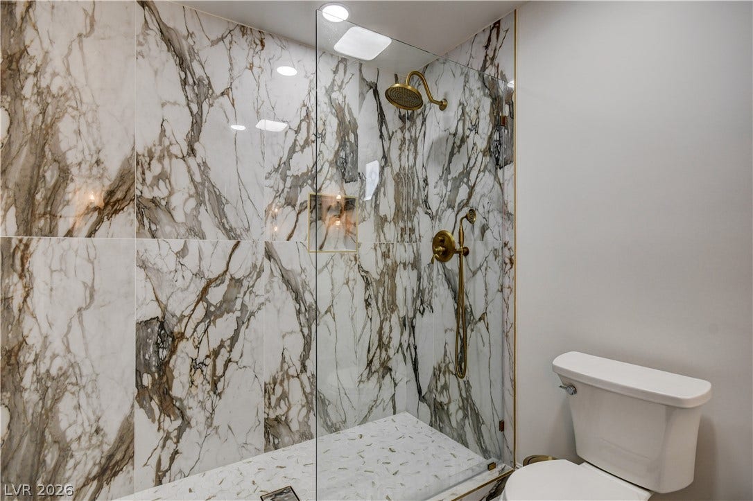 Bold marble tiling and gold hardware define this walk-in shower.