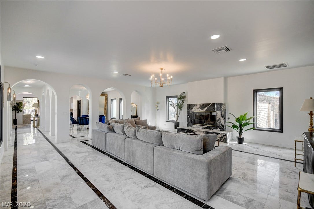 Polished tile flooring and arched passages define this open living area with a stone fireplace.