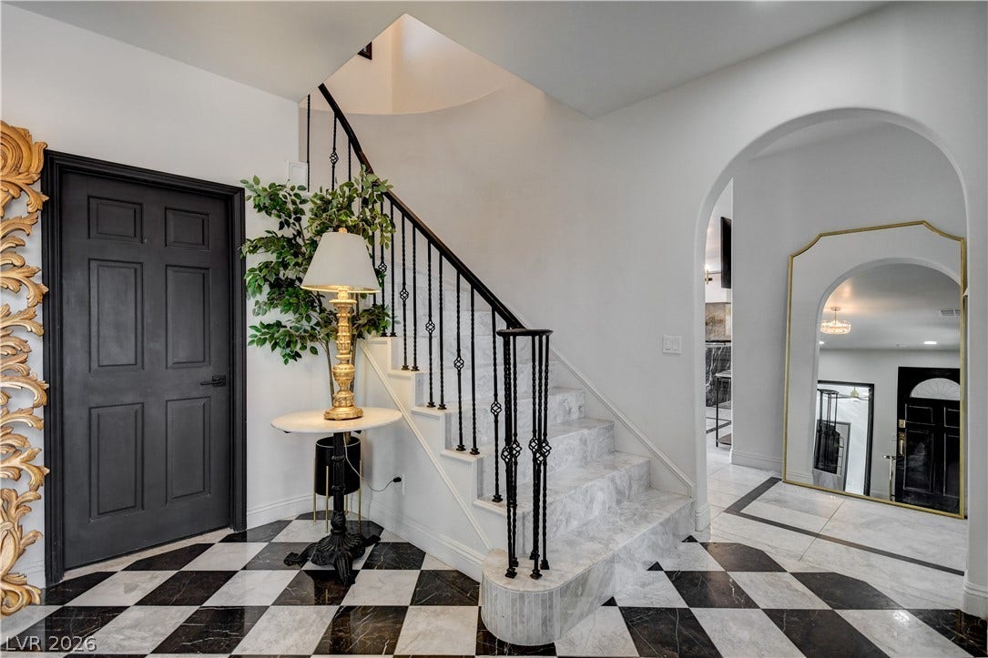 Striking checkered tile floors and a marble staircase define this elegant entryway.