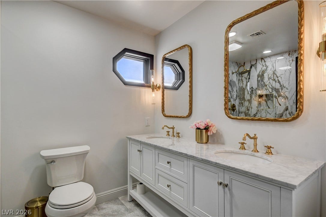 Elegant gold accents and marble countertops define this refined double vanity bathroom.