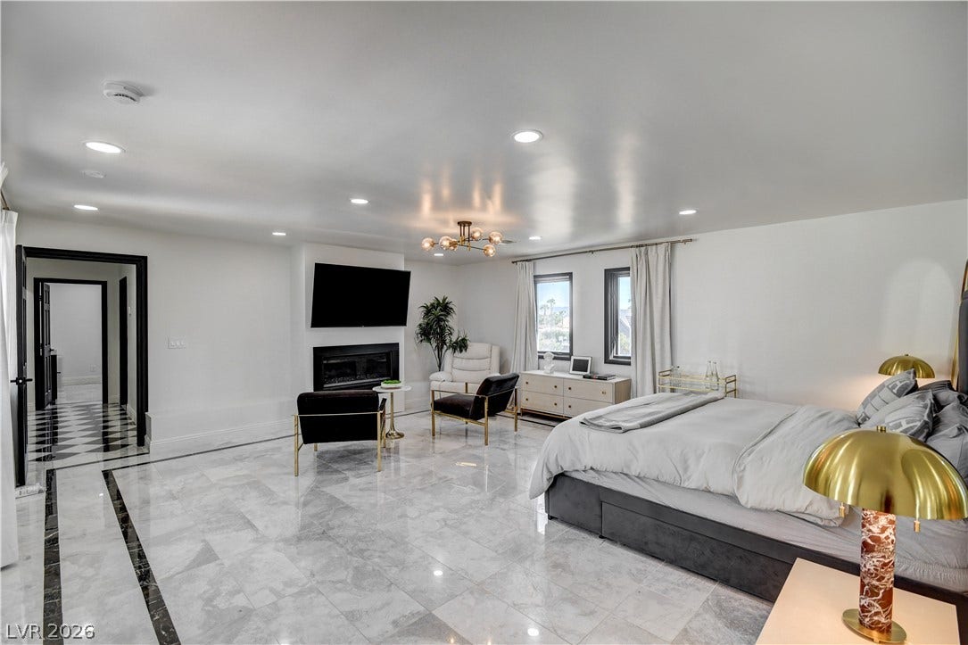 Polished tile flooring and a sleek fireplace anchor this generously proportioned bedroom suite.