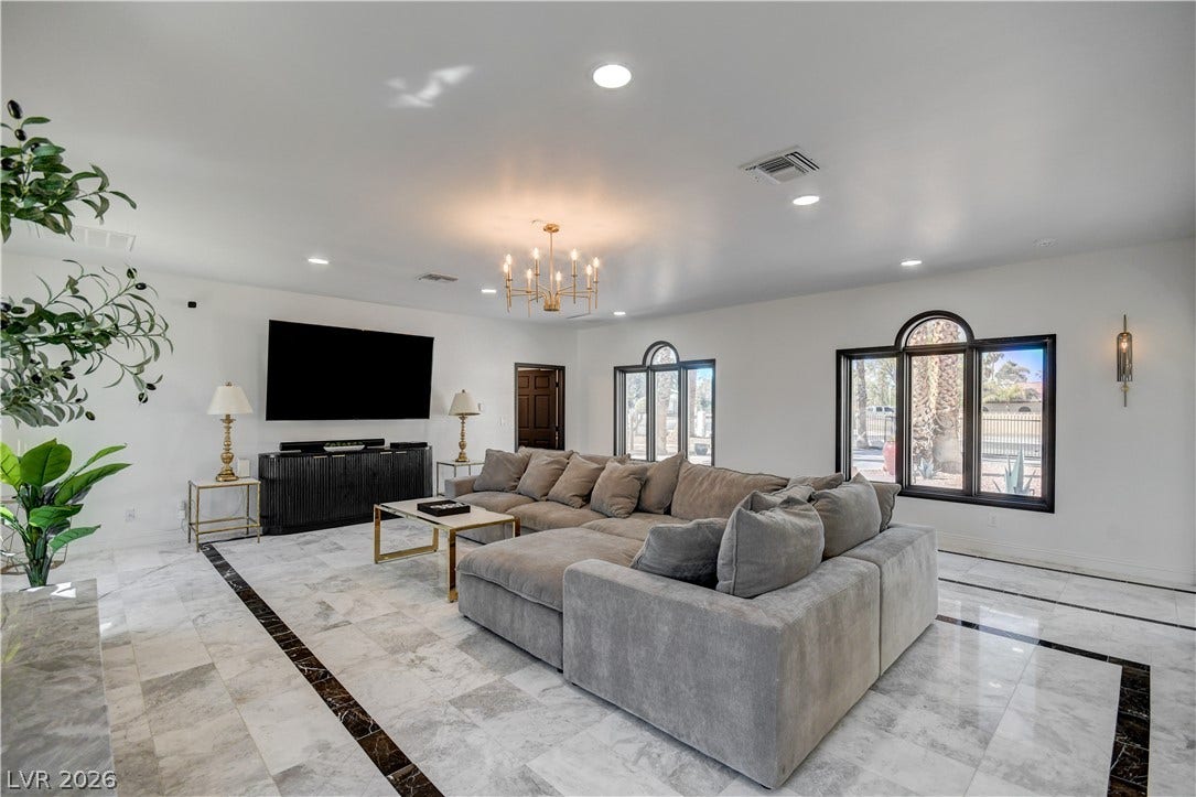 Polished stone flooring and arched windows define this elegant, light-filled living space.