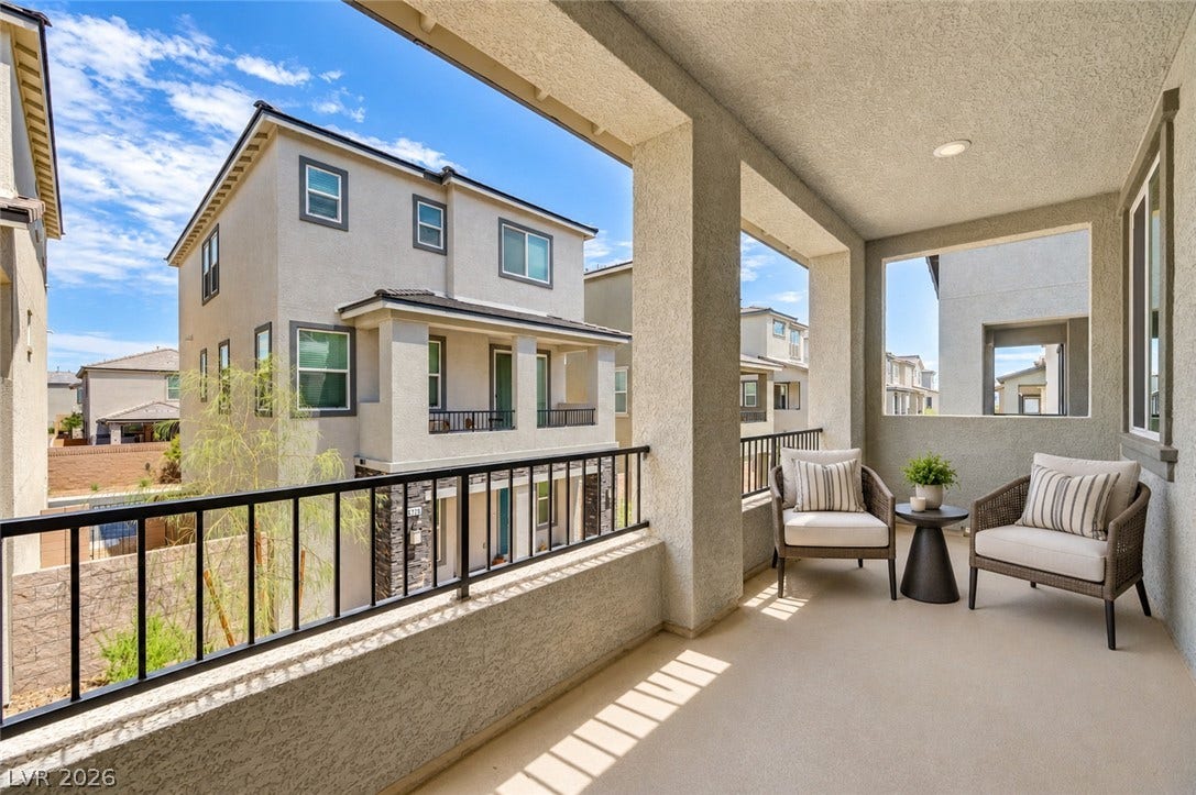 An elevated, covered balcony overlooks neighboring architecture under clear blue skies.